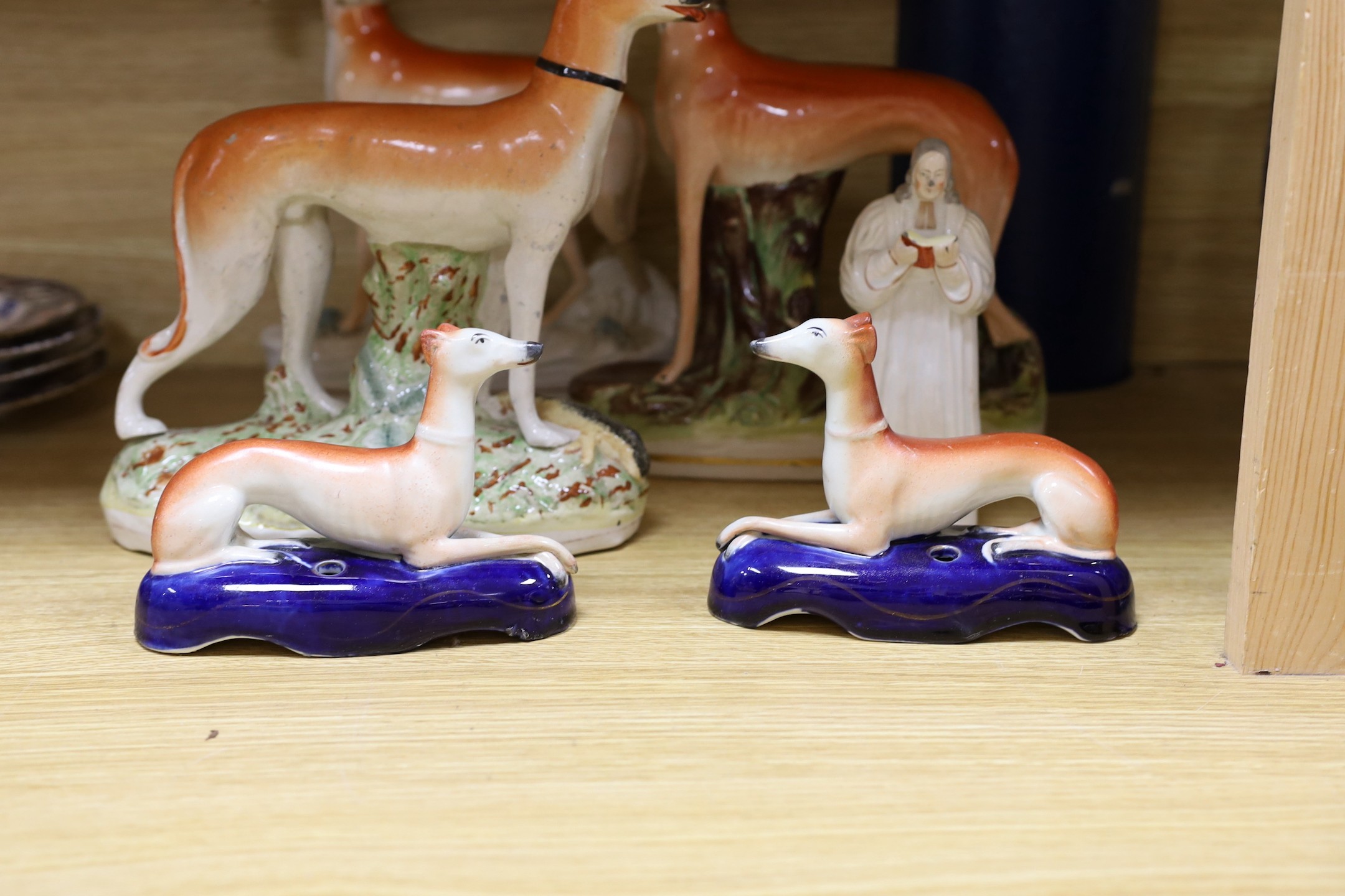 A Staffordshire pottery figure of John Wesley, six Staffordshire pottery models of hounds, and a white bisque group of two hounds on a cushion, tallest 29cm, (8)